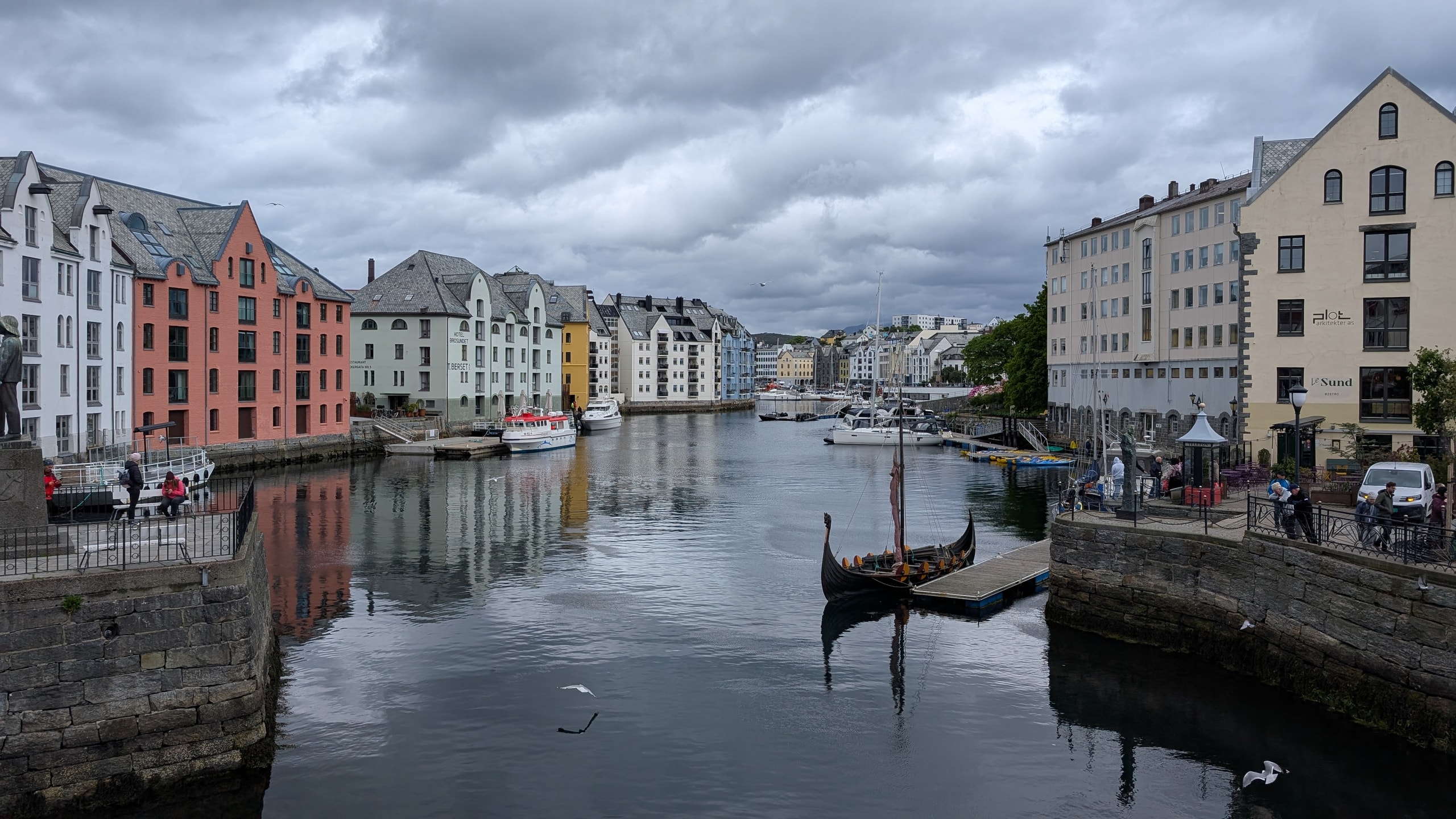 Looking down Brosundet canal in Ålesund with pastel Art Nouveau buildings, moored boats, and seagulls over the water