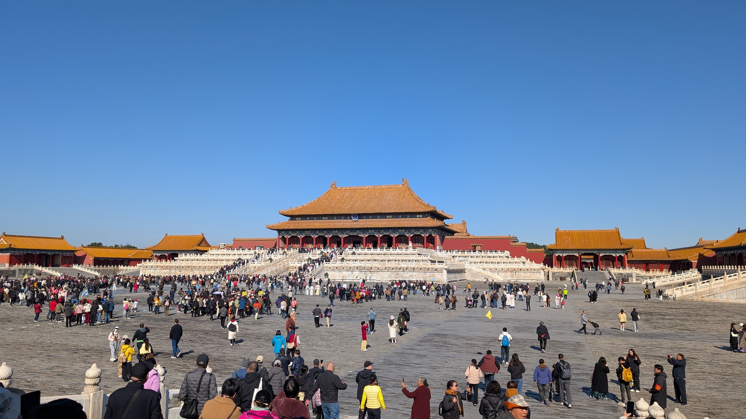 Visitors spread across a vast stone courtyard before the Hall of Supreme Harmony in the Forbidden City