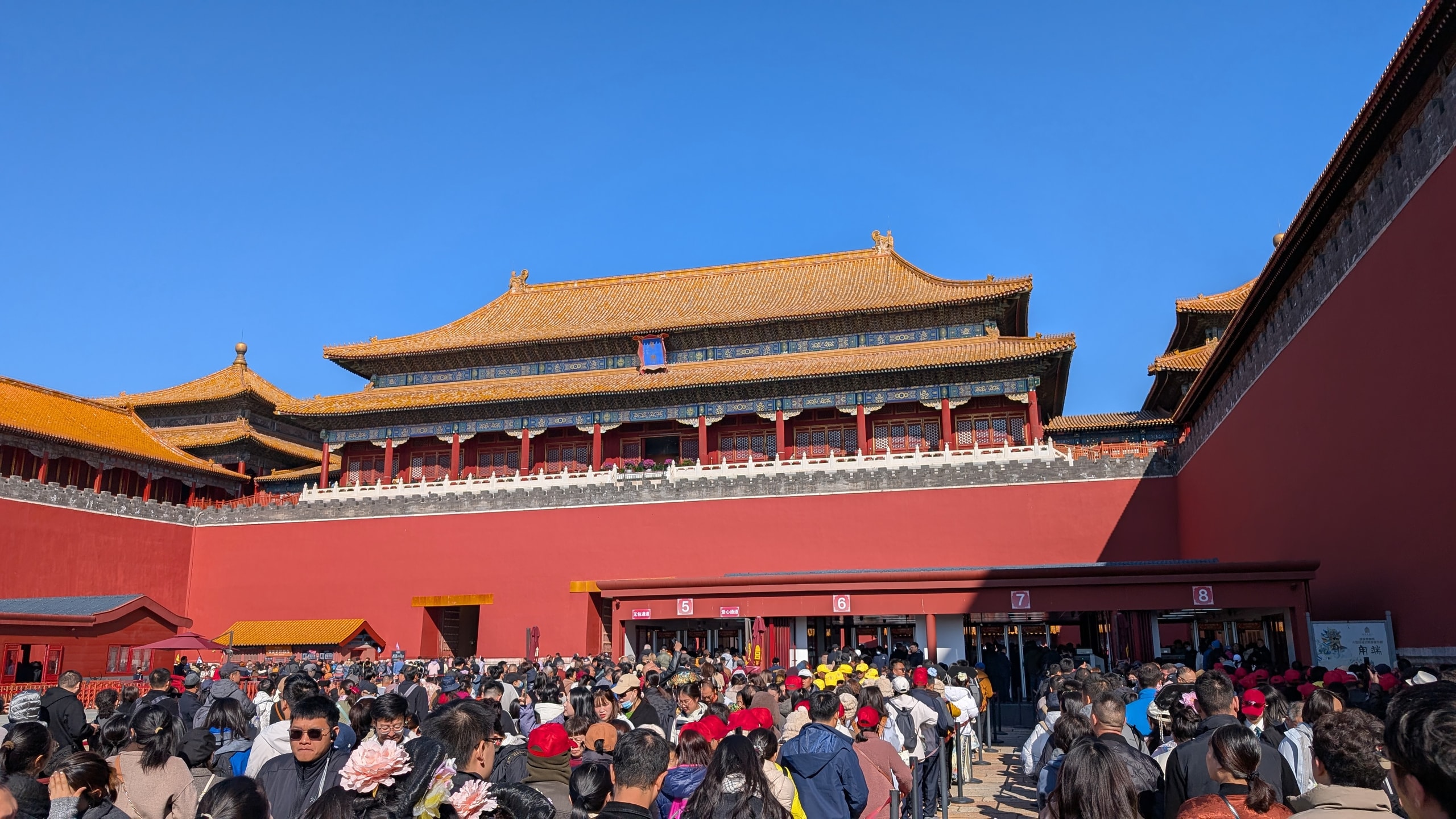 A dense crowd waiting below the red walls and yellow roofs at the Forbidden City's Meridian Gate