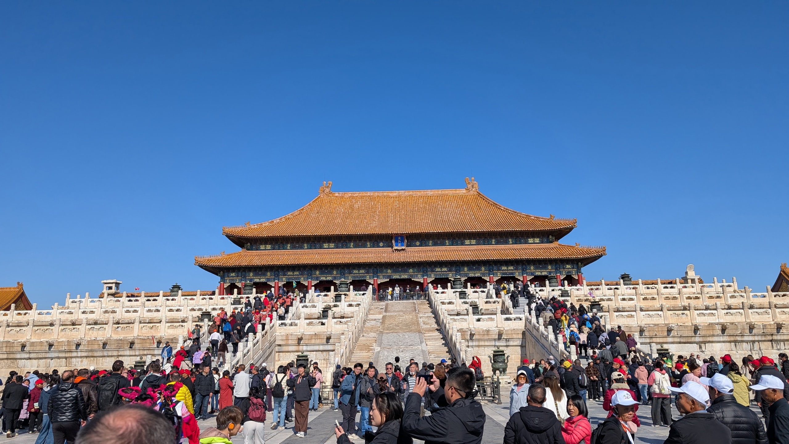 Visitors crowd the stone staircases leading to an ornate yellow-roofed ceremonial hall in the Forbidden City