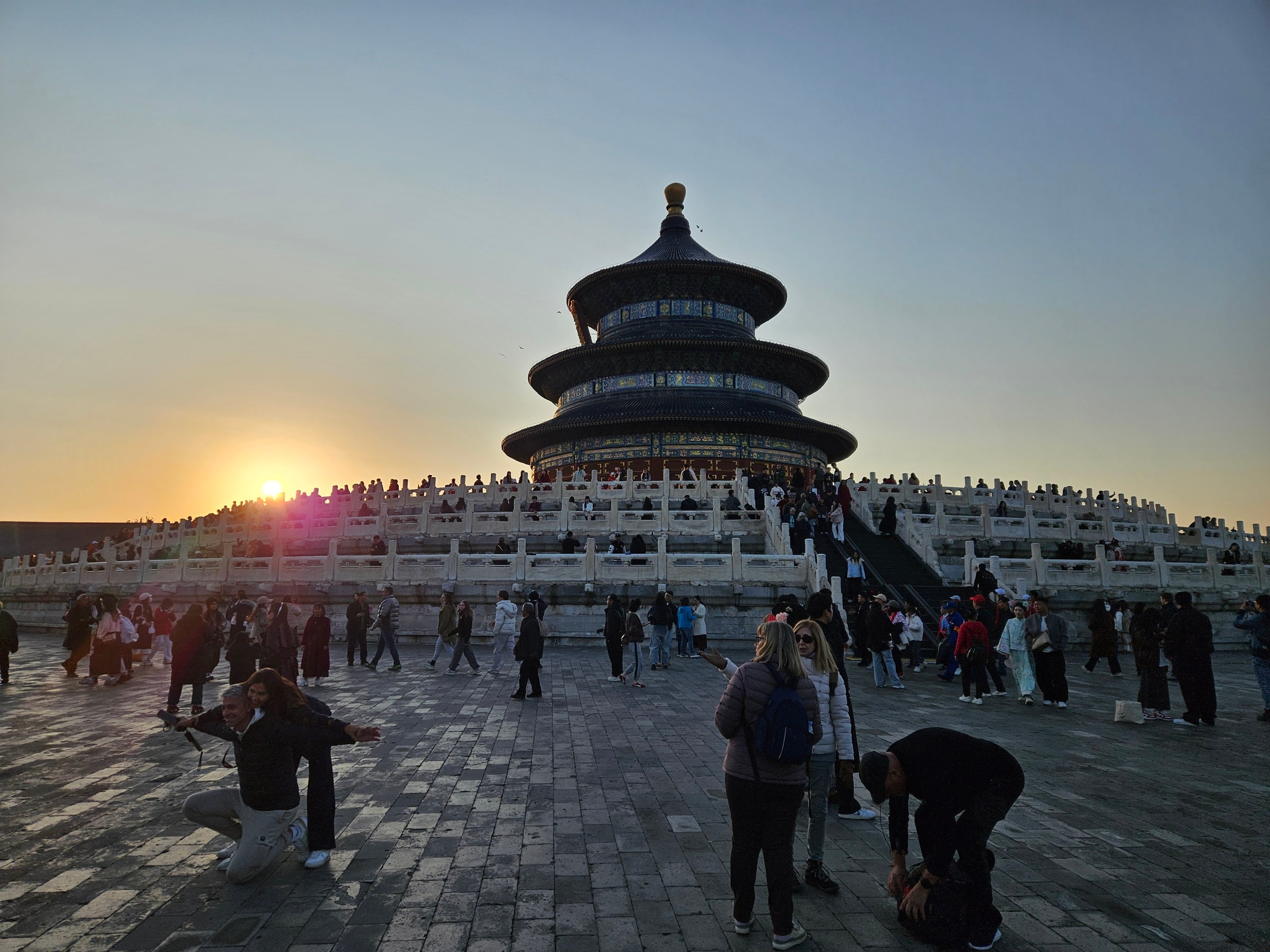 The circular blue-roofed Hall of Prayer for Good Harvests at sunset with visitors on its white stone terraces