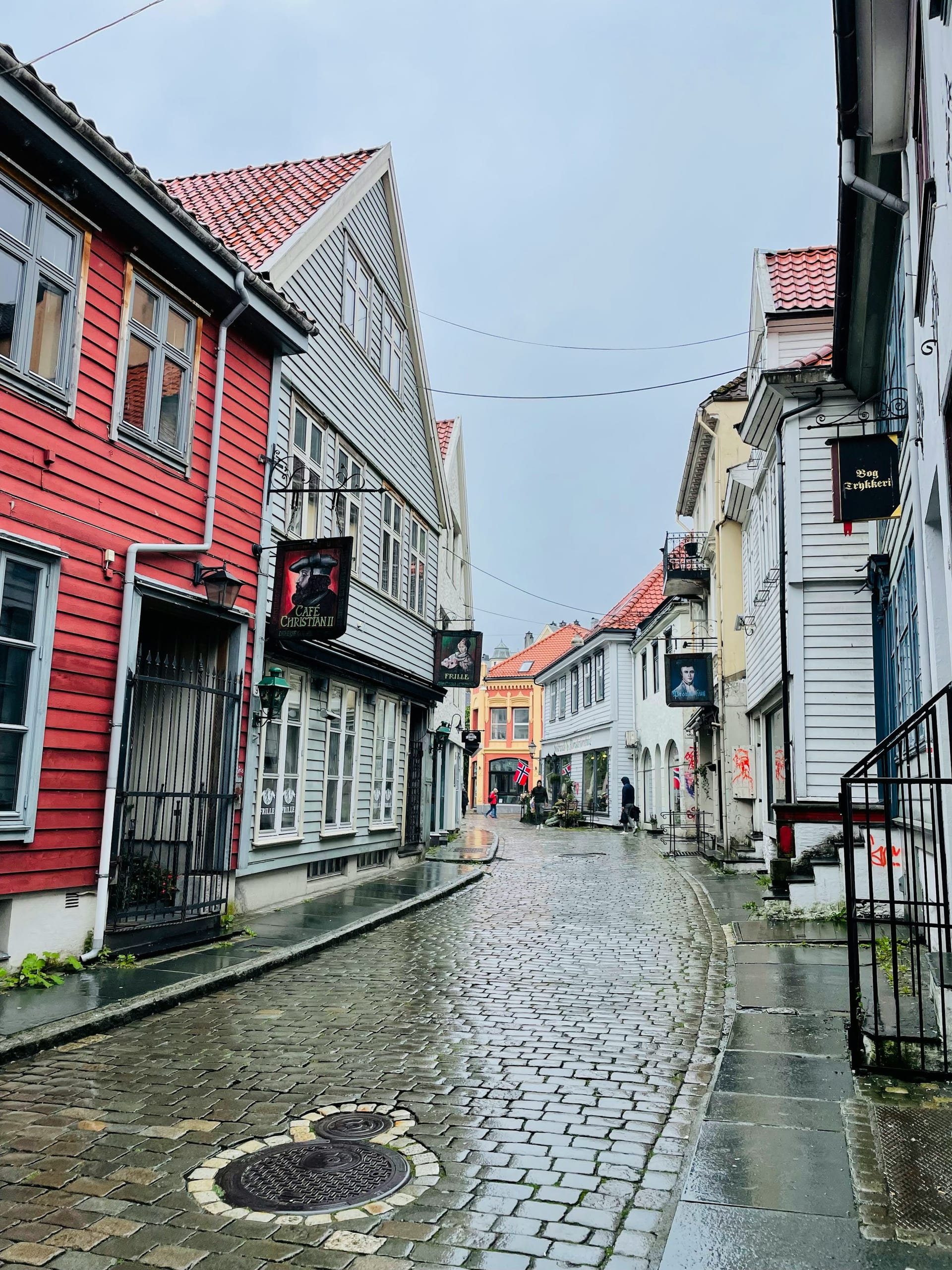 A narrow cobblestone alley between old wooden buildings in Bergen's historic Bryggen district
