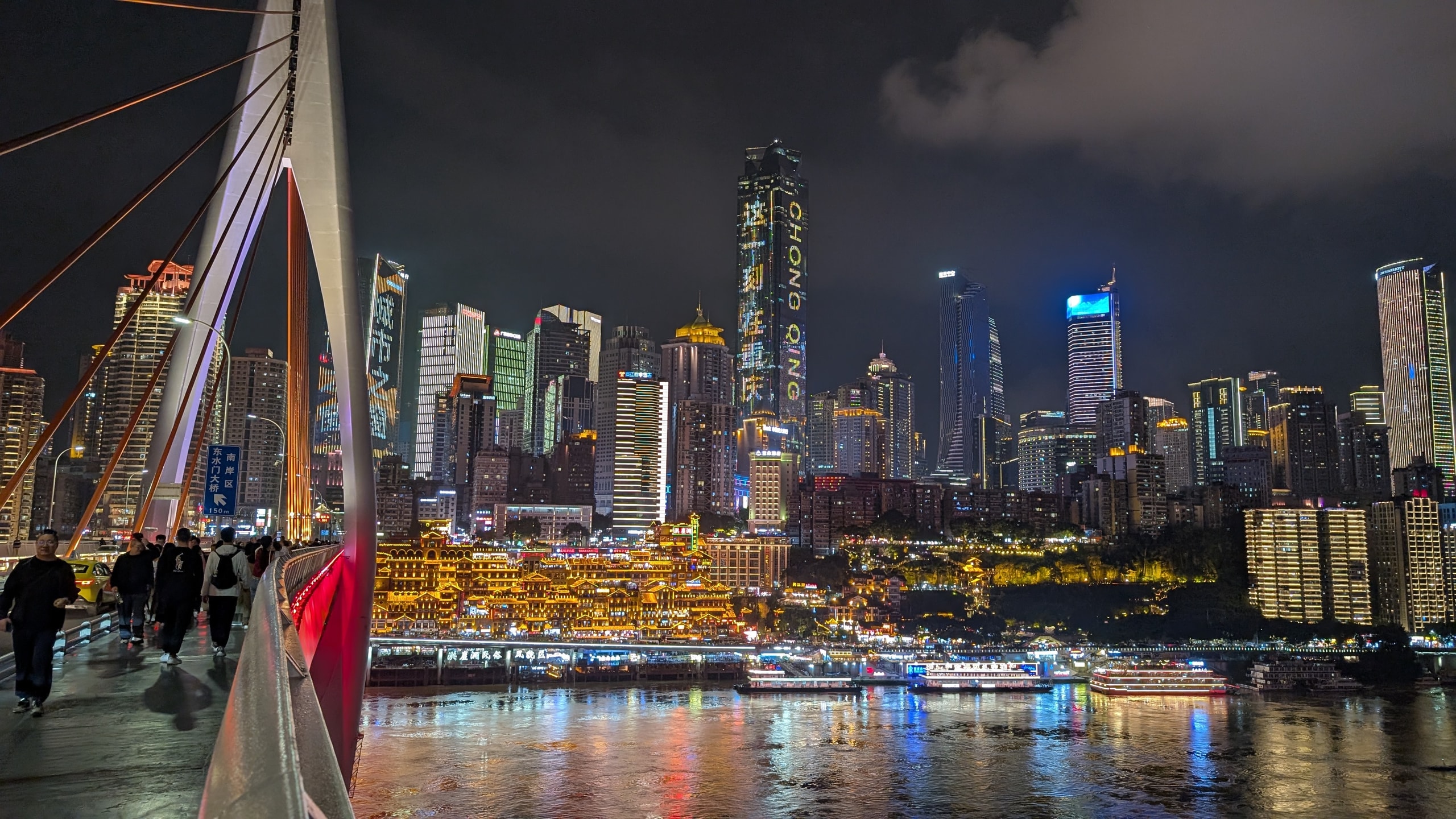 Chongqing skyline at night from a bridge, with Hongyadong lit gold above the river and skyscrapers behind