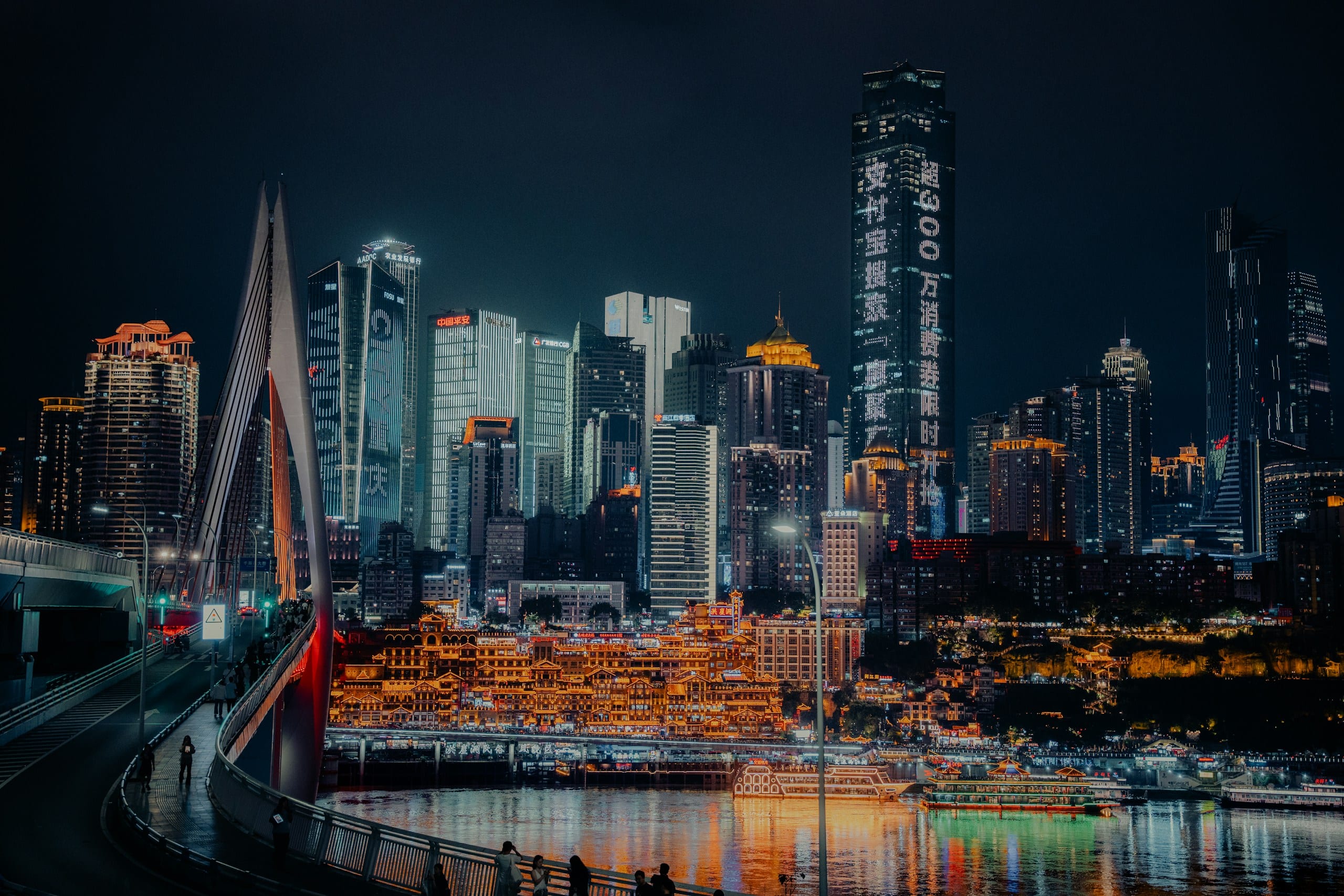 Chongqing skyline and riverfront skyscrapers illuminated at night reflecting on dark water