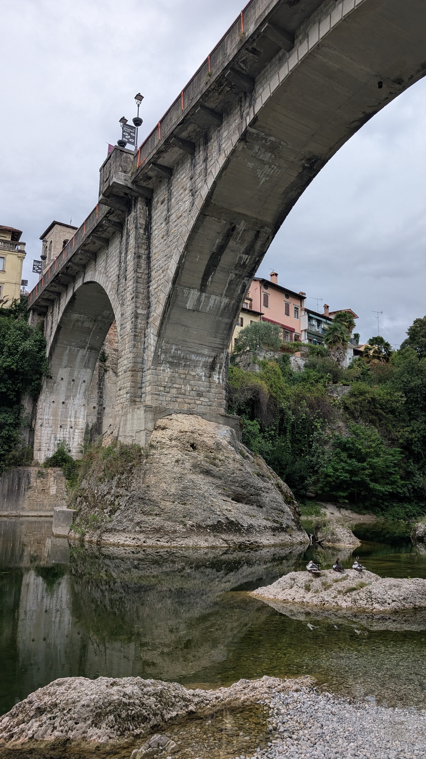 The two stone arches of Cividale's Devil's Bridge rising from a limestone boulder above the Natisone River