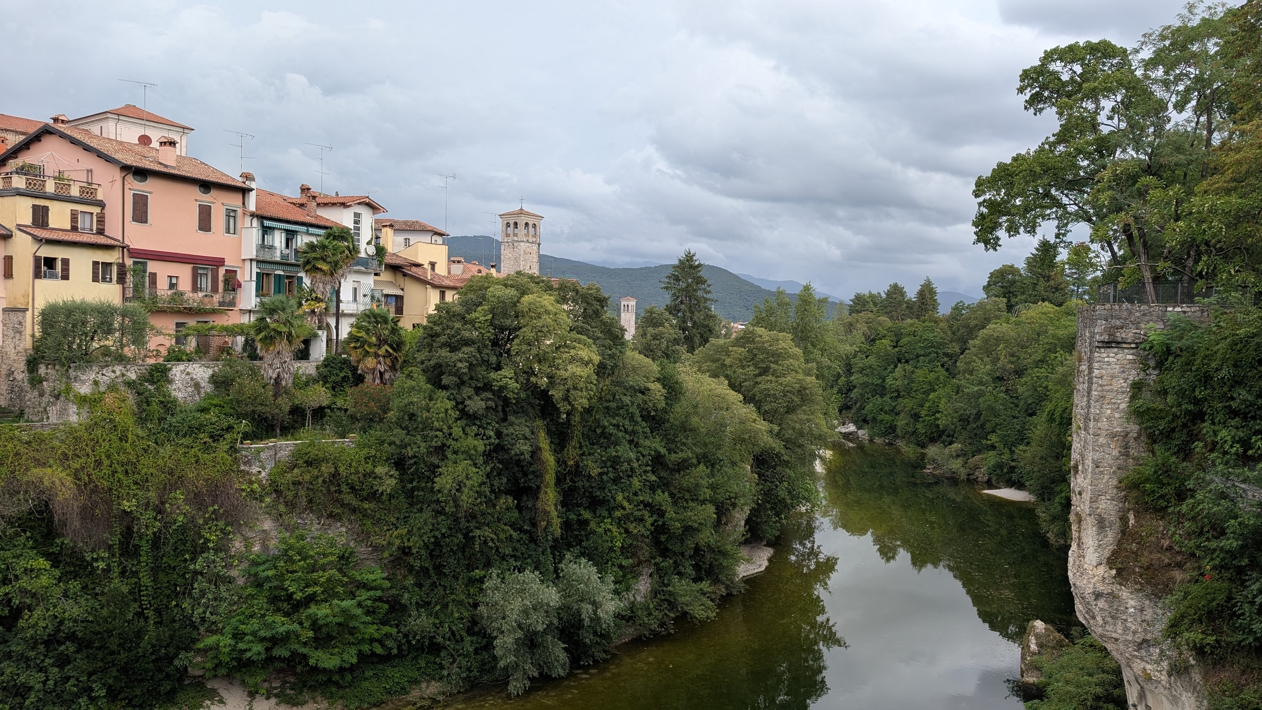 The green Natisone River running through a steep wooded gorge below the pastel houses and stone bell towers of Cividale del Friuli