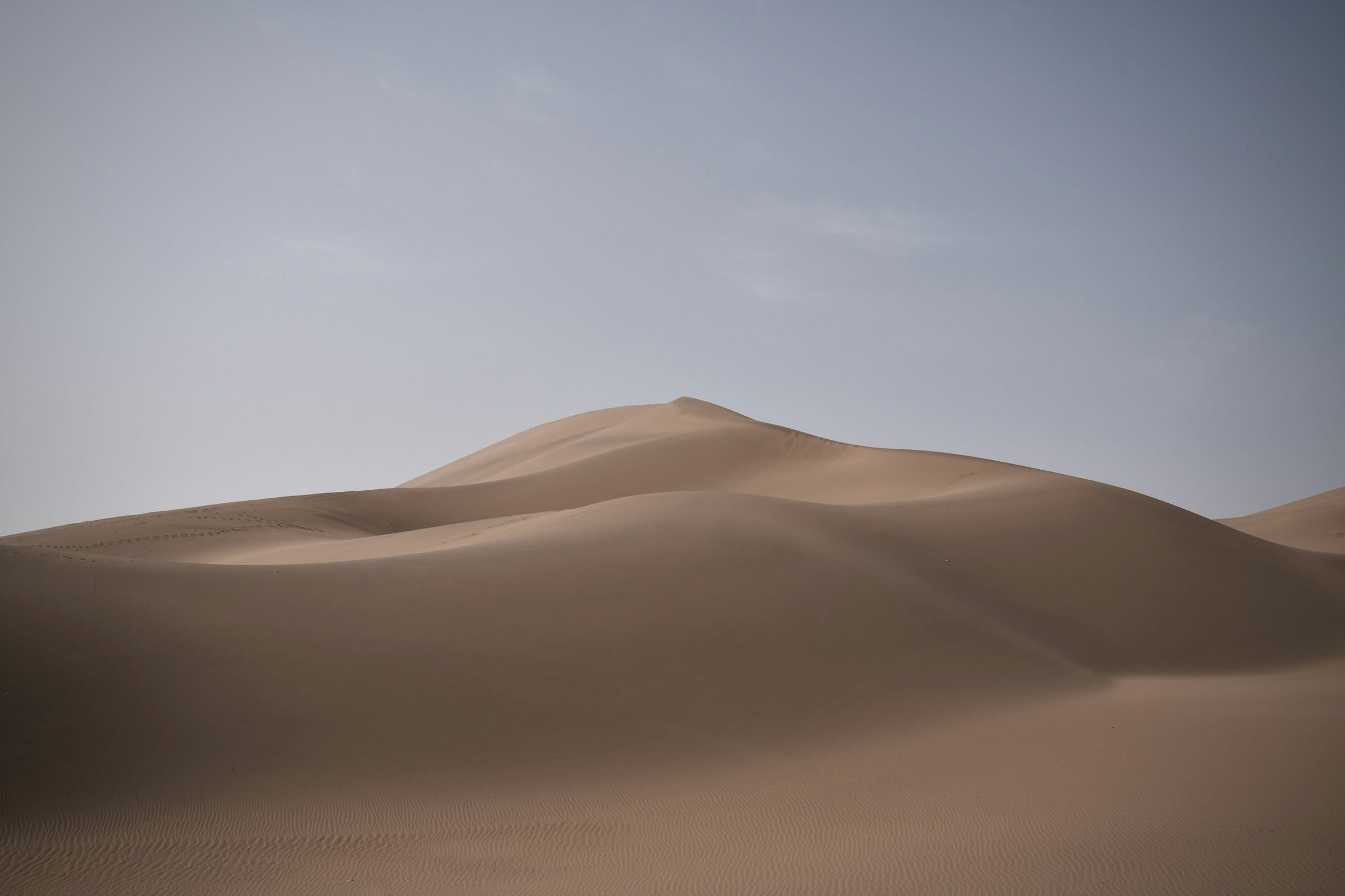 Bare sand dunes under a pale sky at Mingsha Mountain near Dunhuang in Gansu