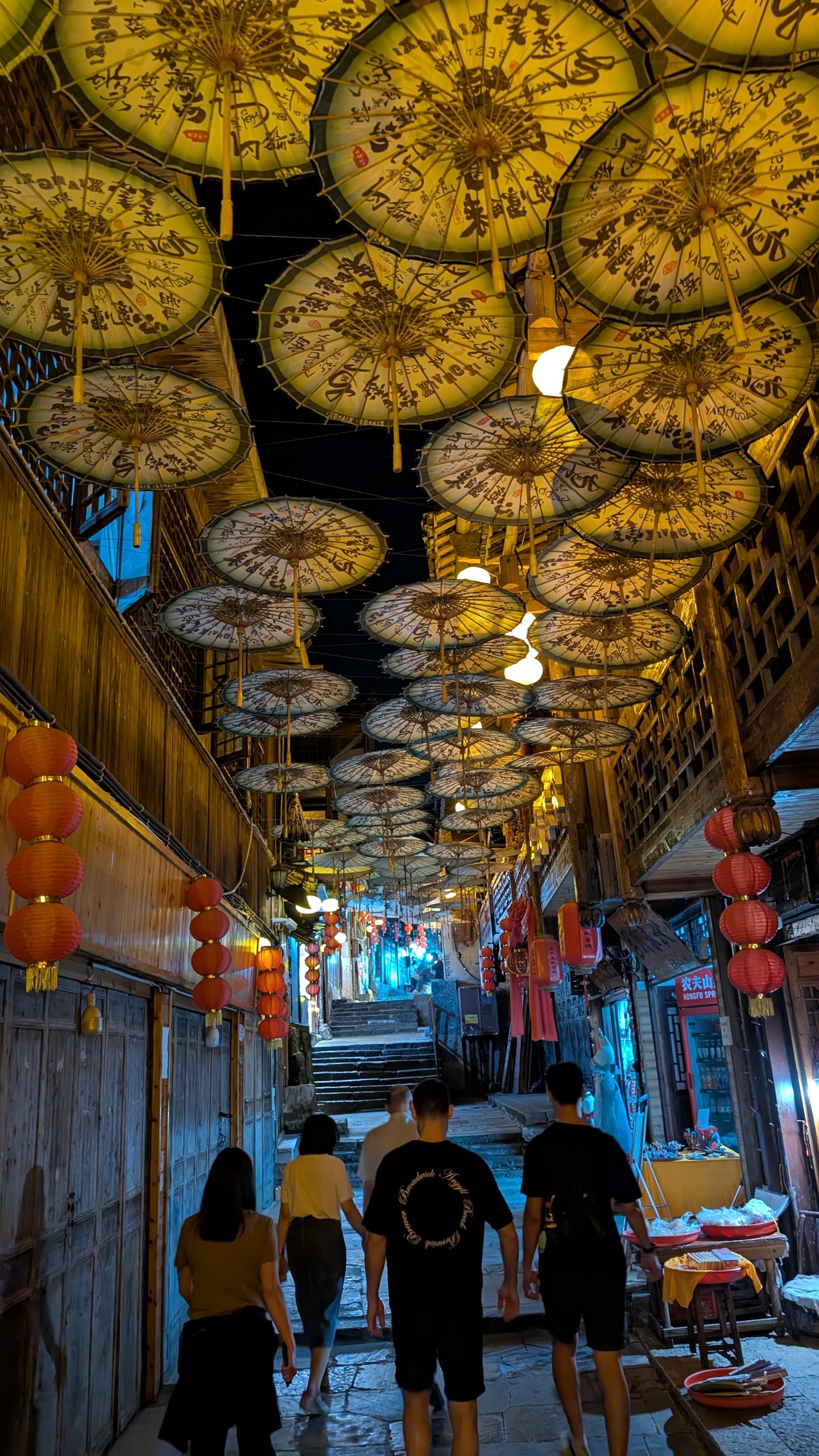Stone-stepped alley in Furong at night under a canopy of illuminated oil-paper umbrellas with calligraphy