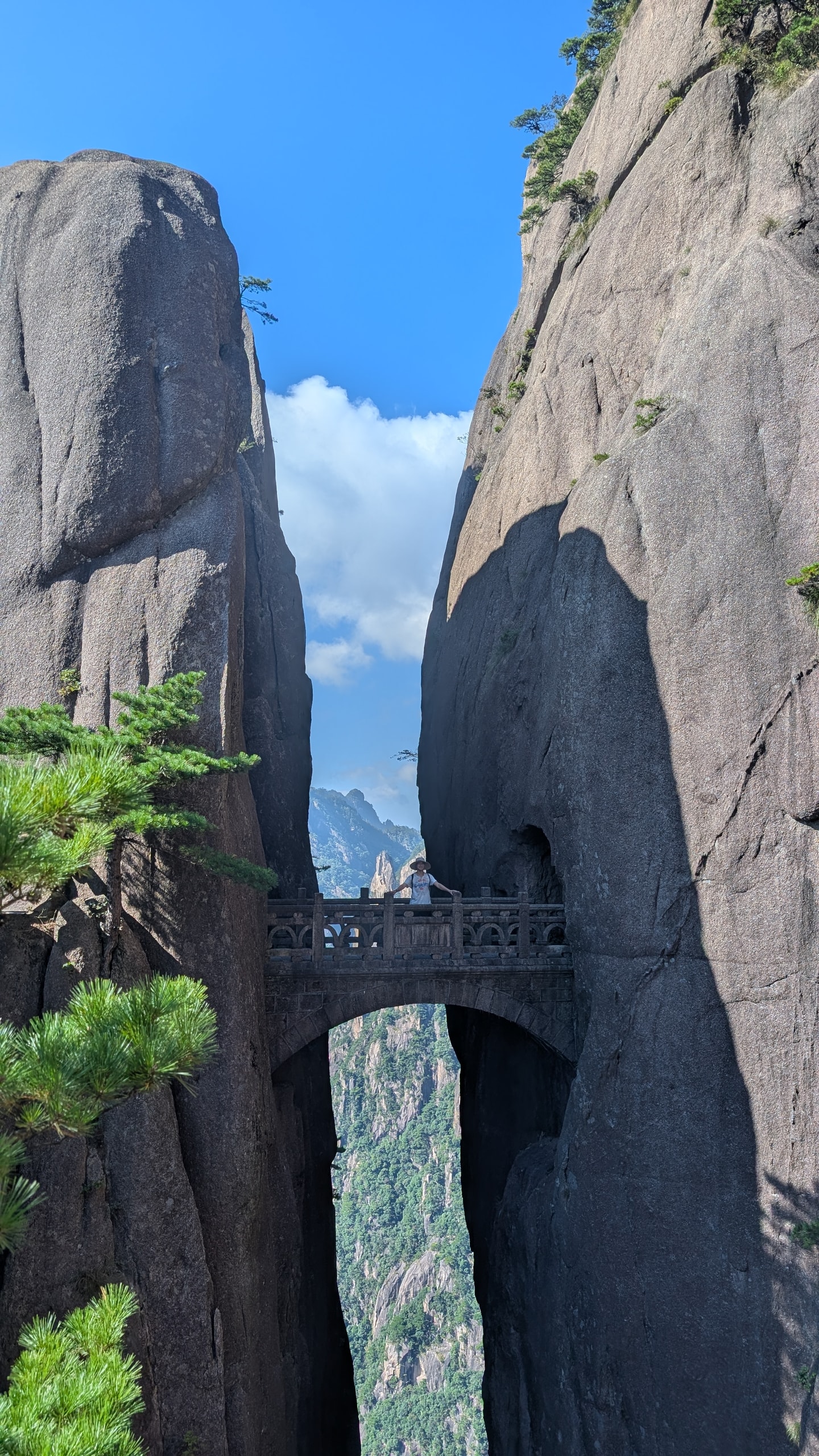 Hiker with arms outstretched on Fairy-walking Bridge between two sheer Huangshan granite cliffs