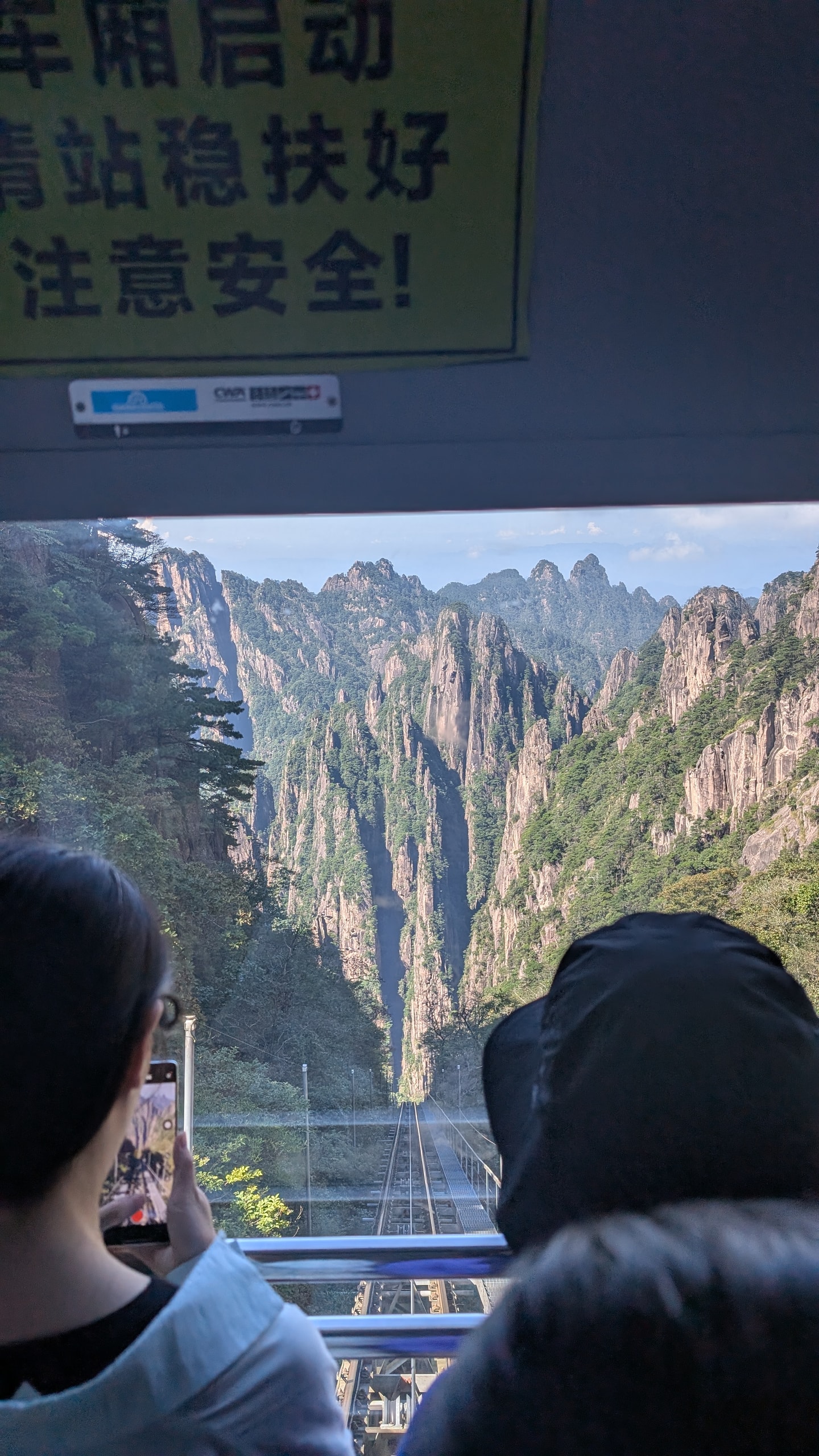 View down the steep West Sea Grand Canyon funicular rails between Huangshan granite peaks from inside the car
