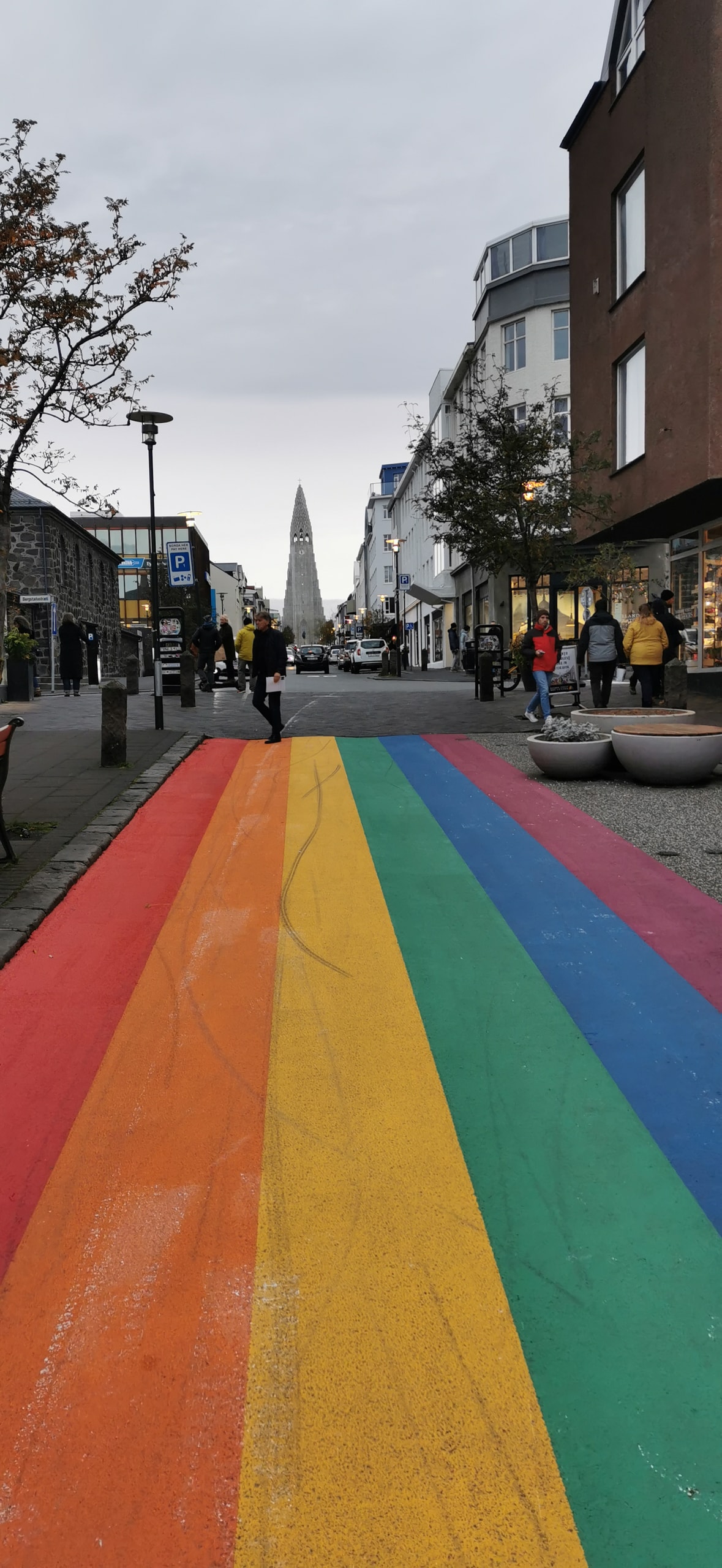 Rainbow-painted street in Reykjavik leading toward Hallgrímskirkja church under an overcast sky