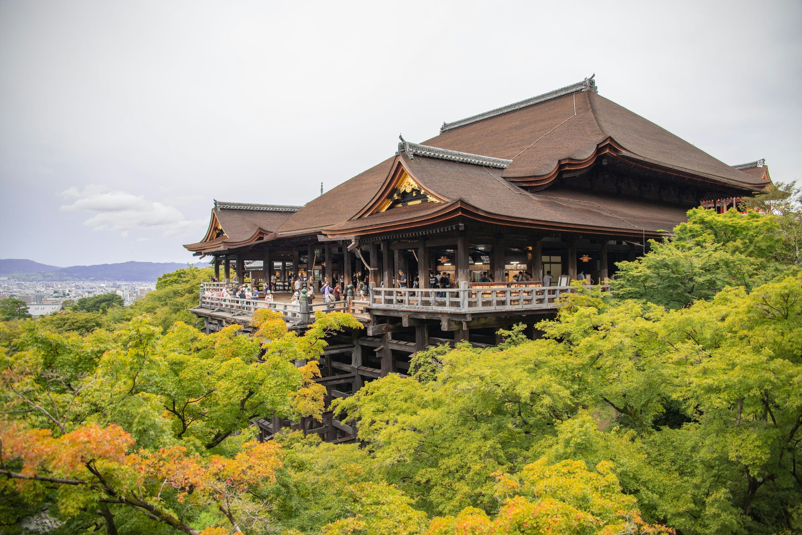 The main hall of Kiyomizu-dera temple surrounded by trees on a hillside in Kyoto