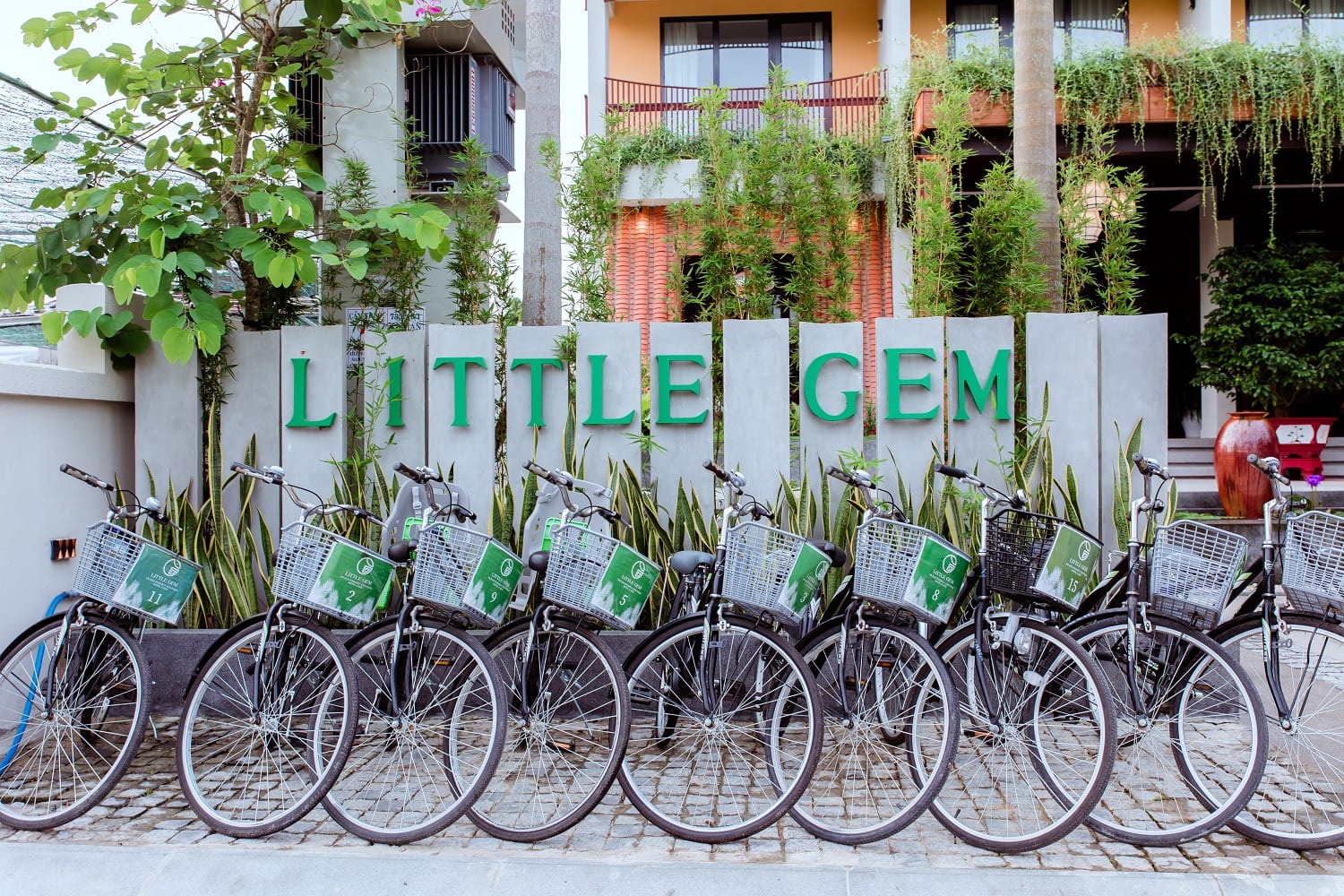 Rows of complimentary bicycles parked under a covered area at Little Gem Hoi An