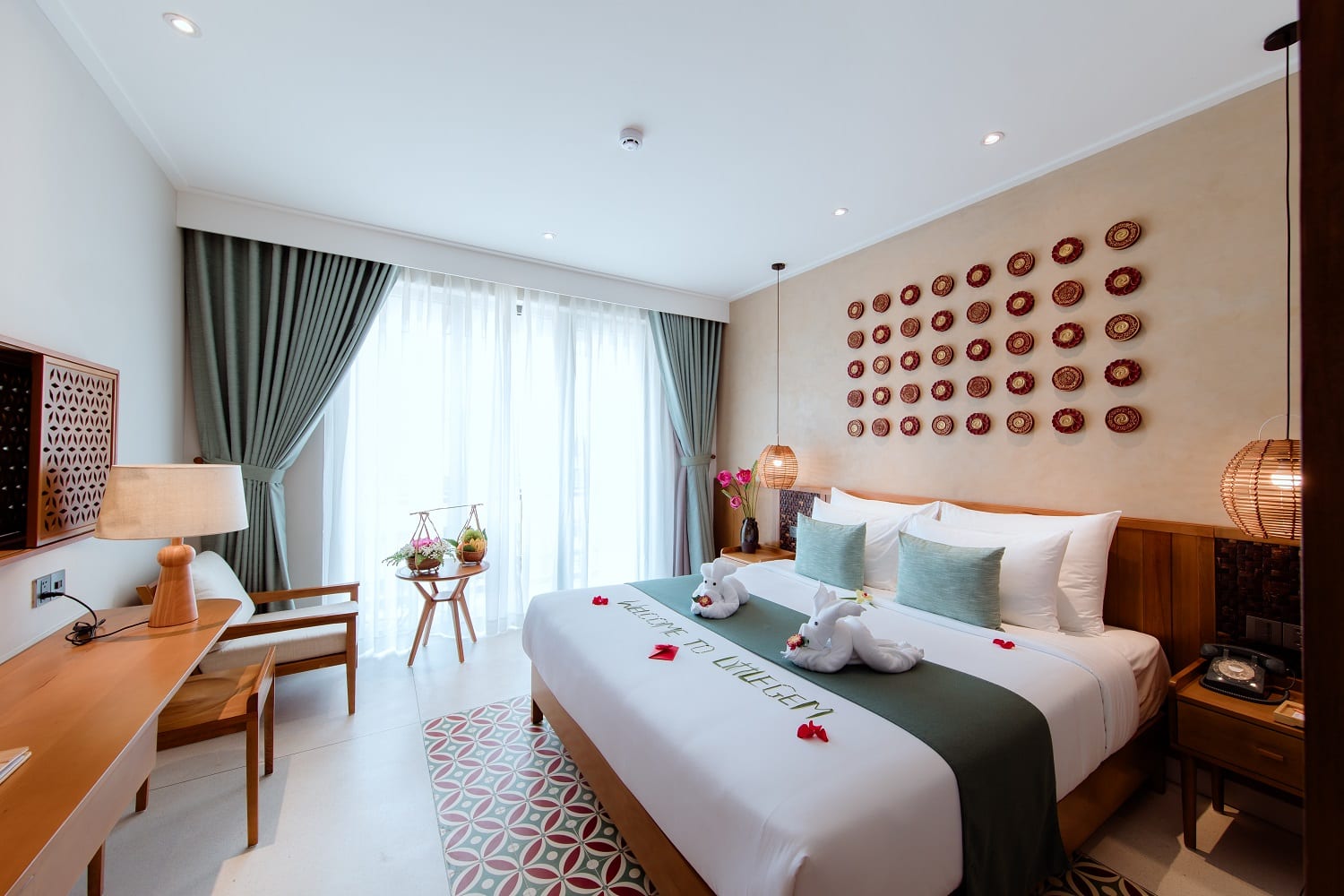 Deluxe hotel room at Little Gem Hoi An with a large bed, wooden furnishings, and soft natural light