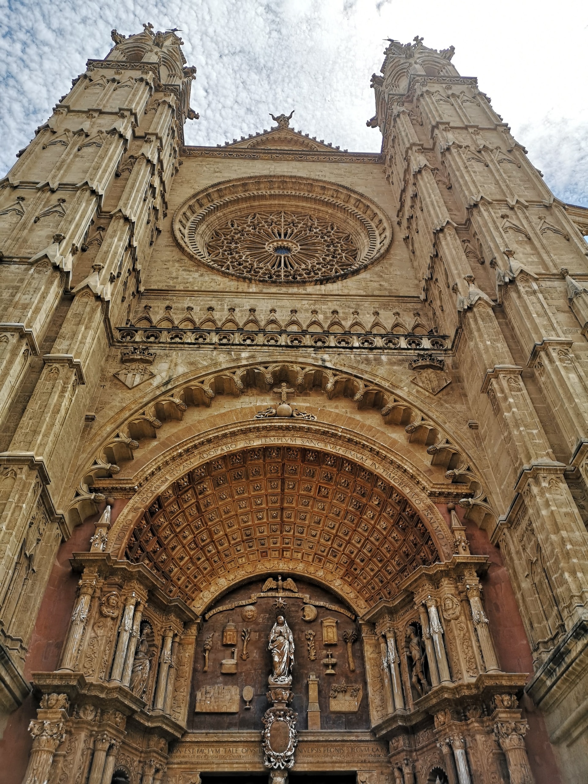 The carved Gothic portal and rose window on the west front of Palma Cathedral viewed from directly below