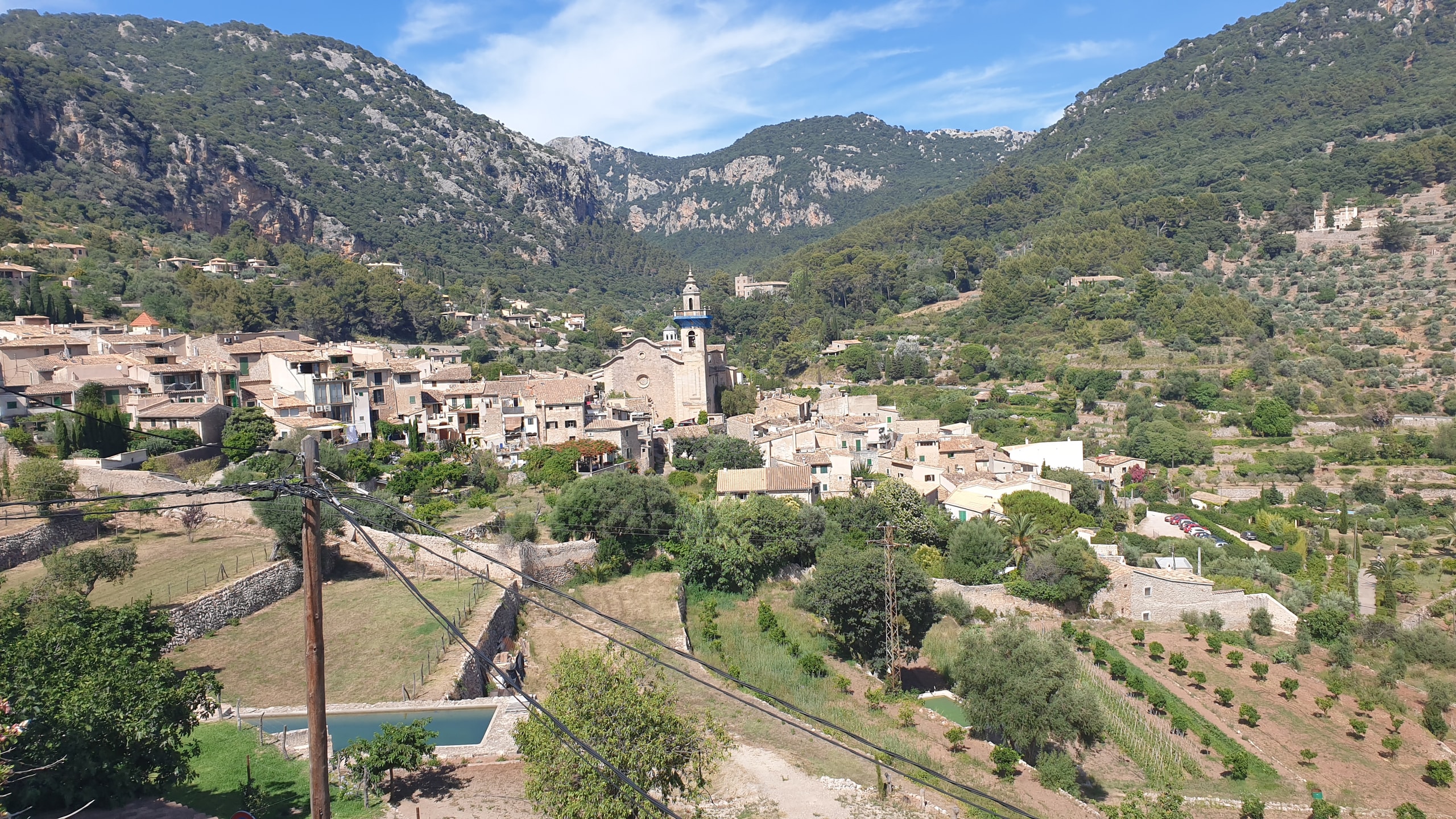 Valldemossa's stone houses and church tower spread across a cultivated valley beneath the Serra de Tramuntana