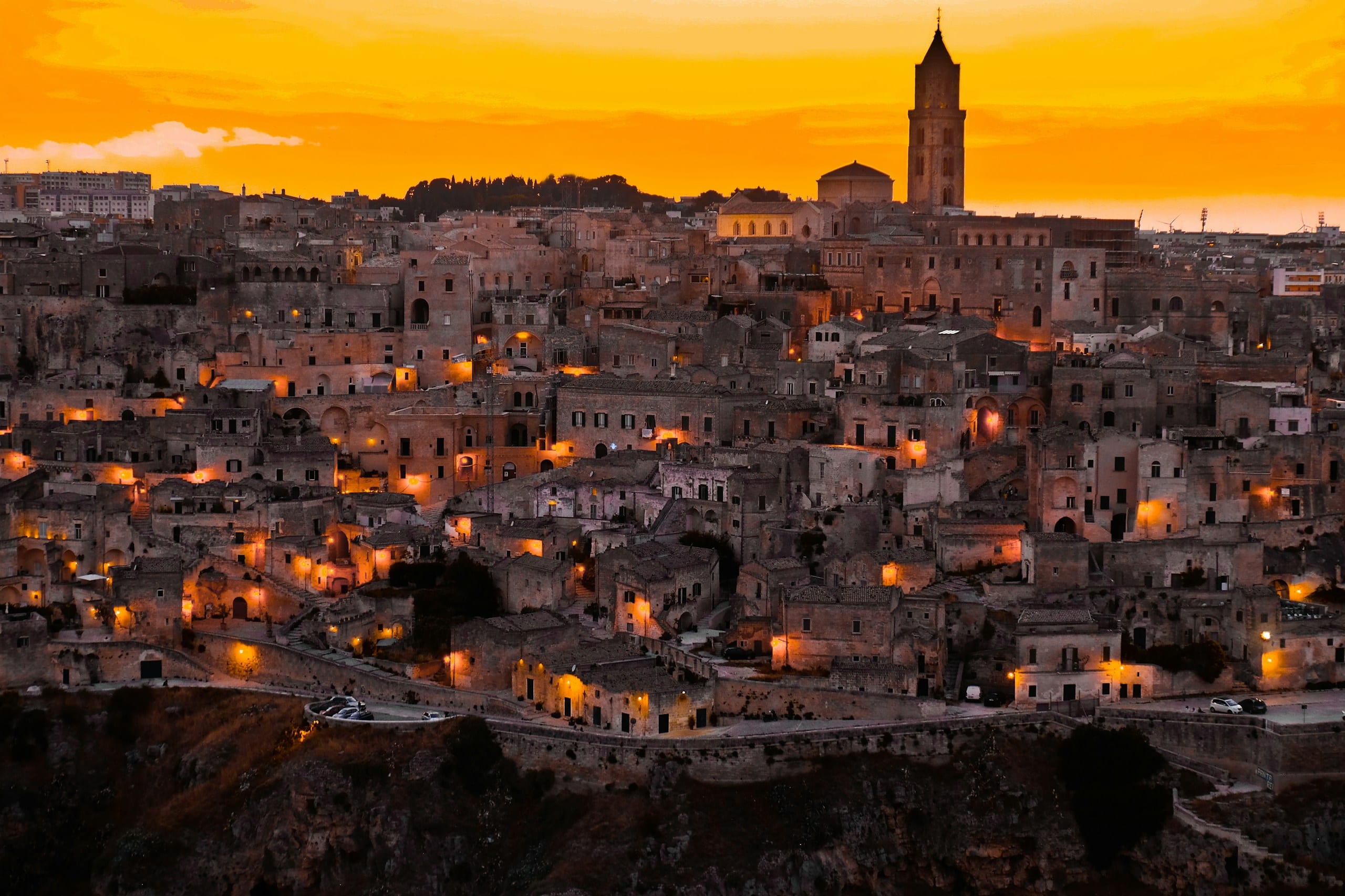 Matera's Sassi cave dwellings and stone houses lit warm gold at dusk above the Gravina canyon