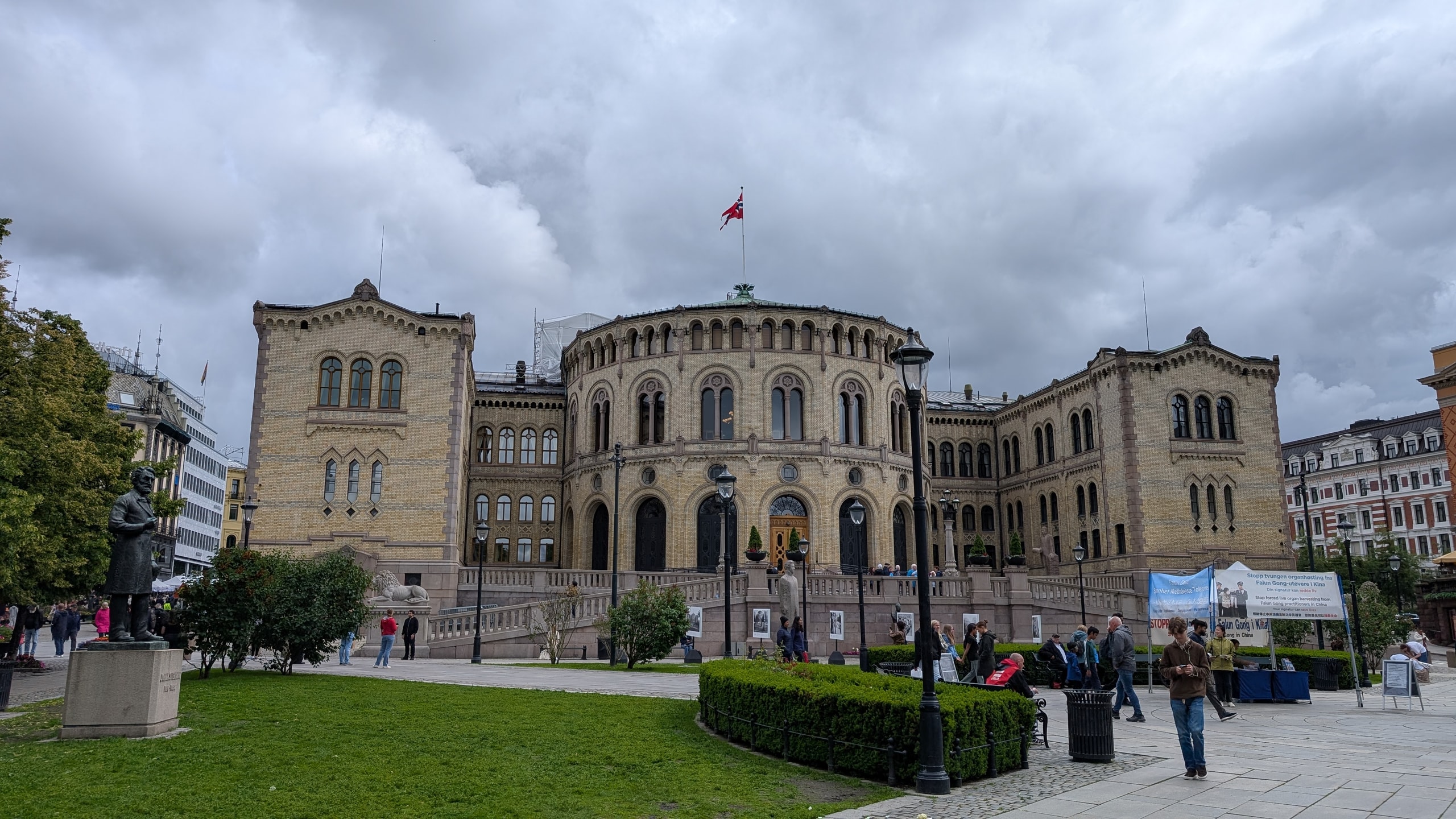 The yellow-brick Storting parliament building on Eidsvolls plass in central Oslo under a cloudy sky