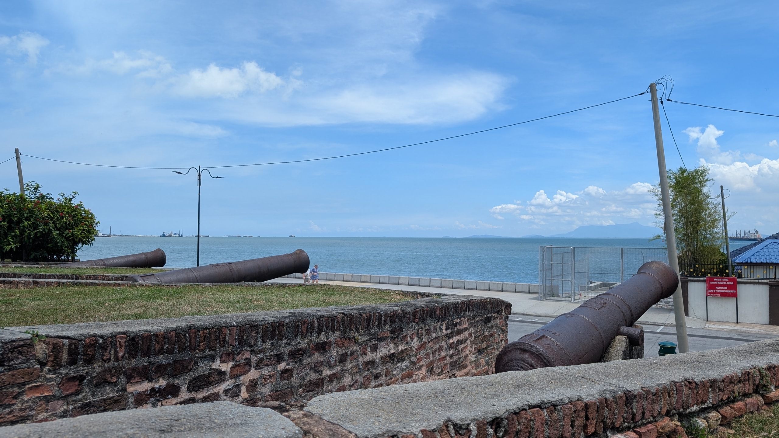 Weathered cannons on the brick ramparts of Fort Cornwallis overlooking the blue Strait of Malacca
