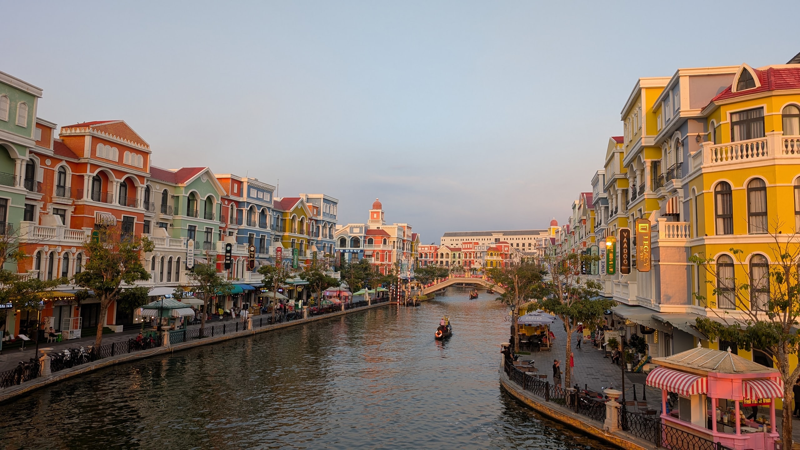 A gondola on the canal at Grand World Phu Quoc, lined with brightly painted Venetian-style buildings at golden hour