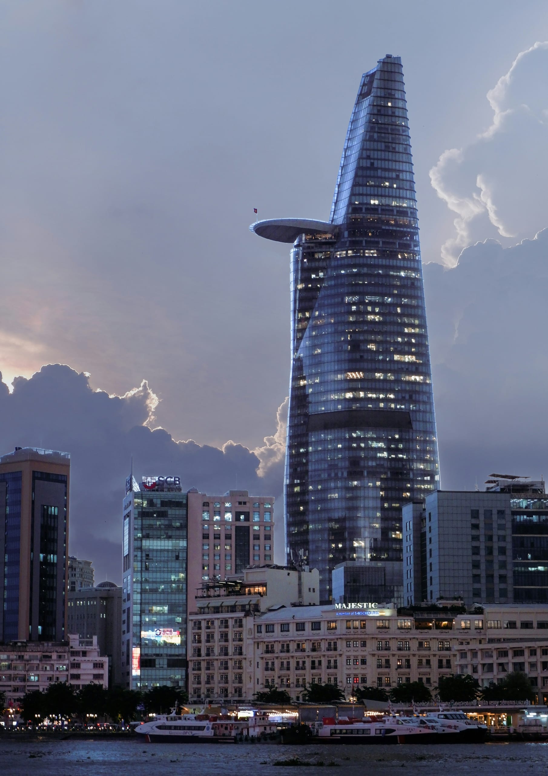 The Bitexco Financial Tower and Ho Chi Minh City skyline at dusk with boats on the Saigon River