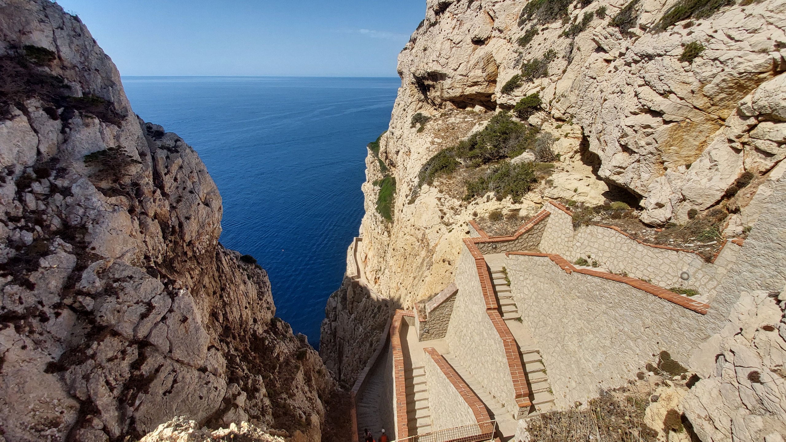 The zig-zag Escala del Cabirol stone staircase descending Capo Caccia’s limestone cliffs toward the blue sea