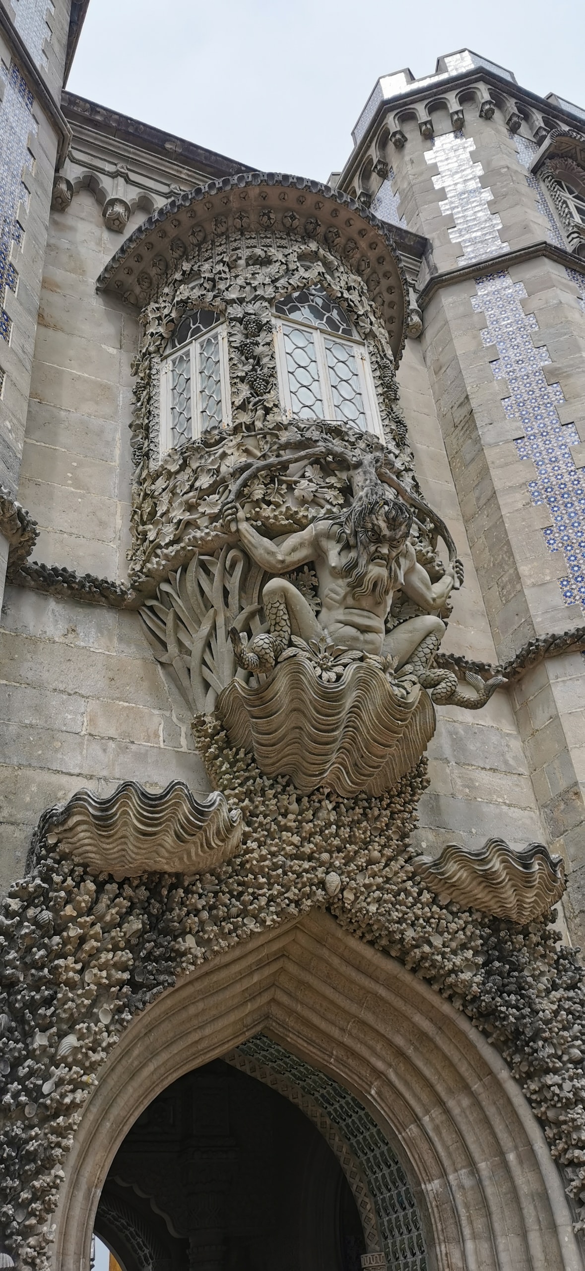 Stone Triton figure bursting from a giant clam shell beneath a carved bay window on the facade of Pena Palace