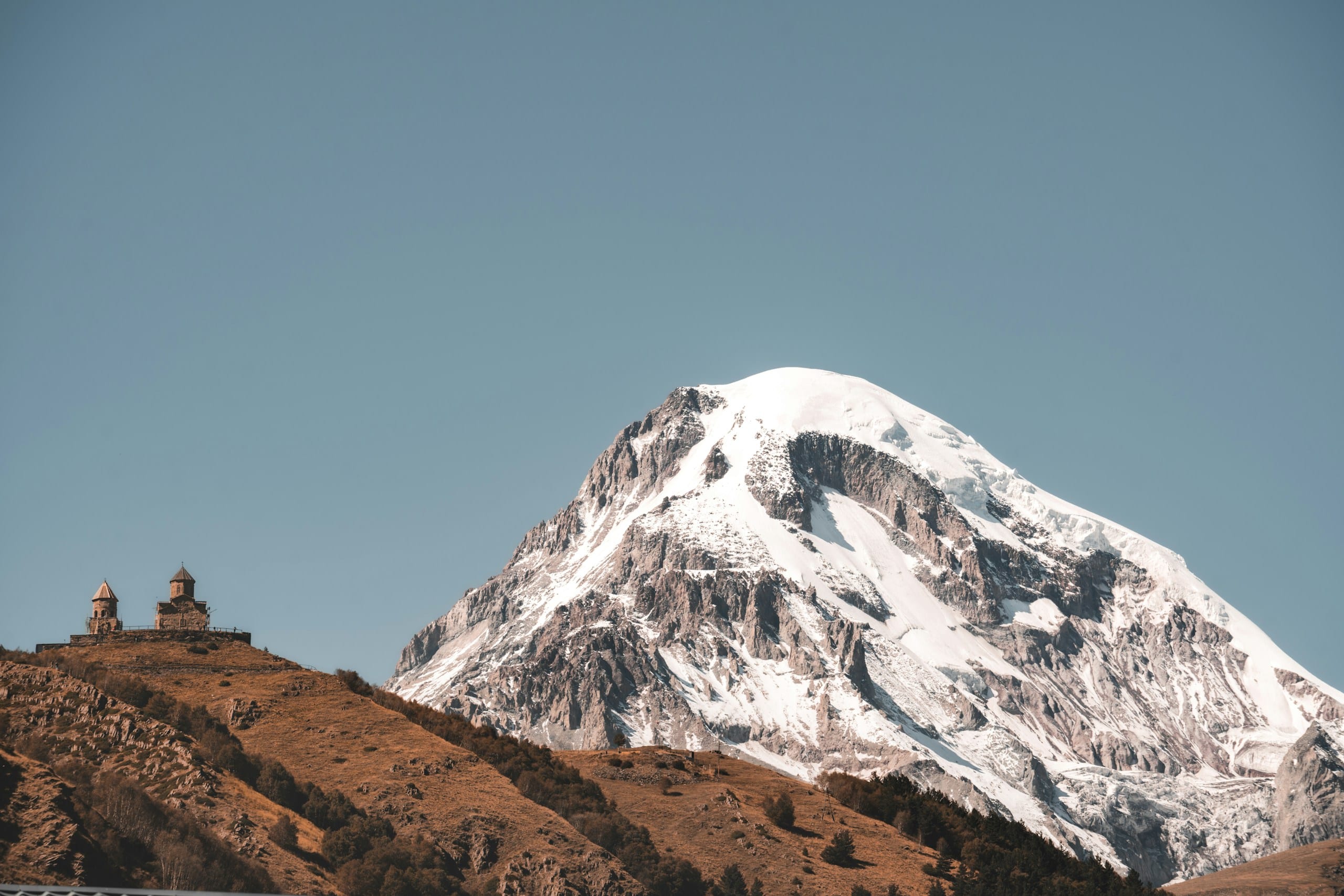 Gergeti Trinity Church on a ridge below the snow-covered peak of Mount Kazbek in Georgia