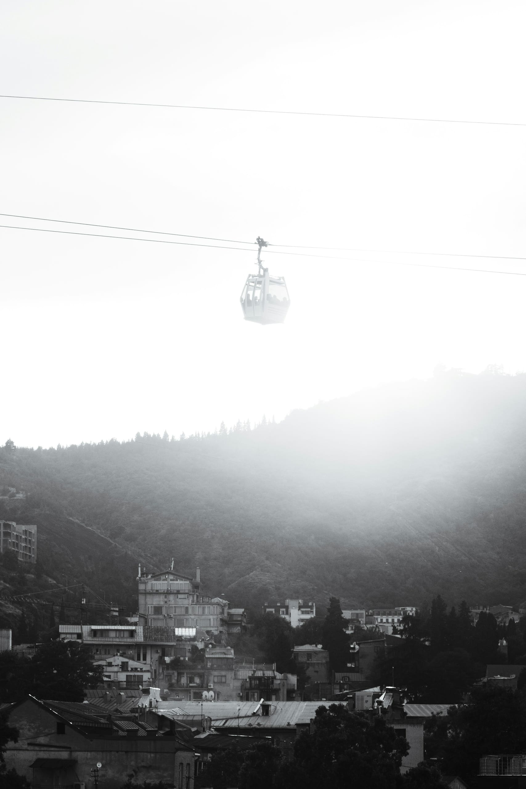 Cable car suspended above Tbilisi's hillside old town and trees on the way toward Narikala fortress
