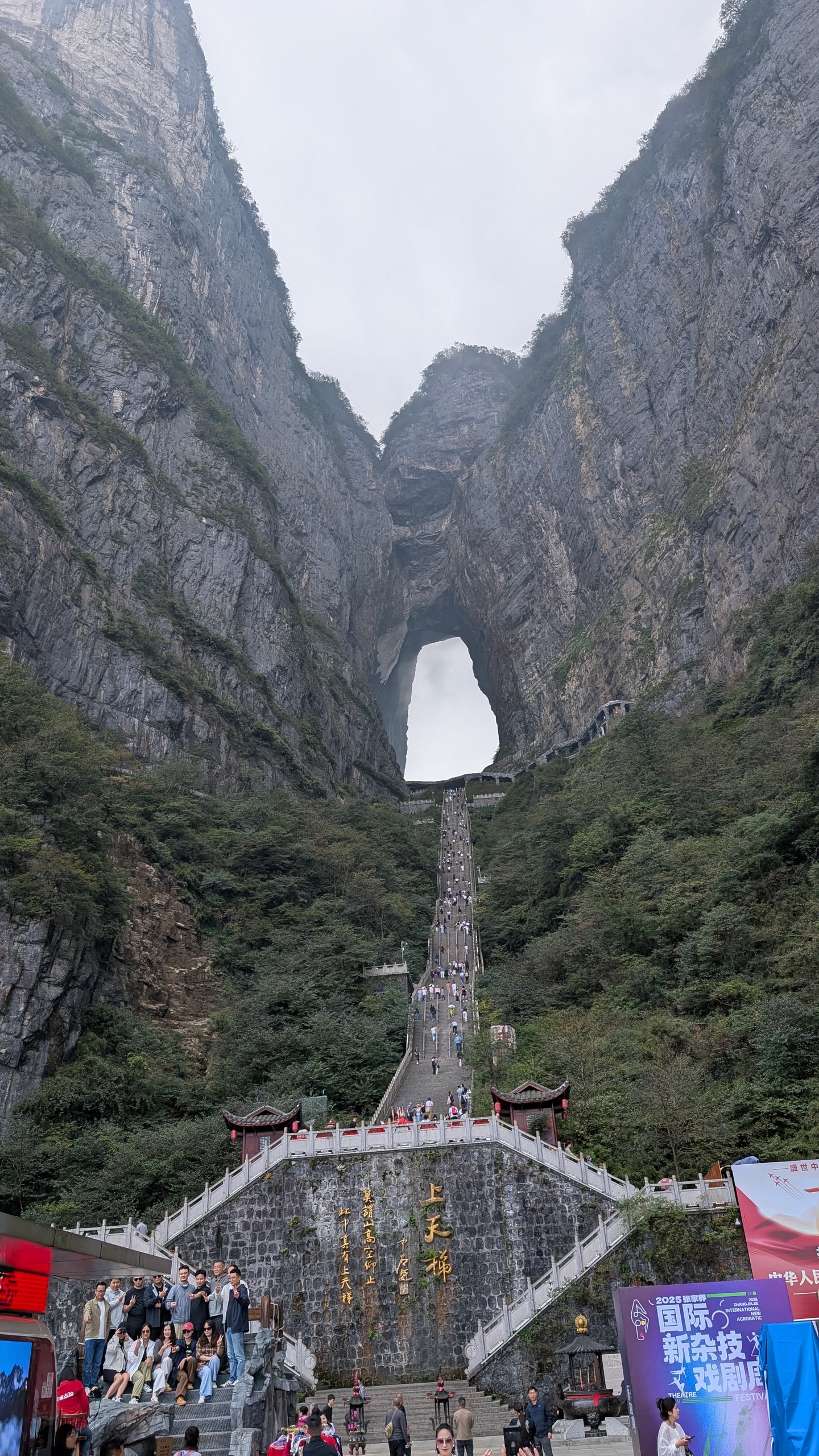 The full staircase to Tianmen Cave seen from the plaza below, with the natural rock arch high above and crowds at the base