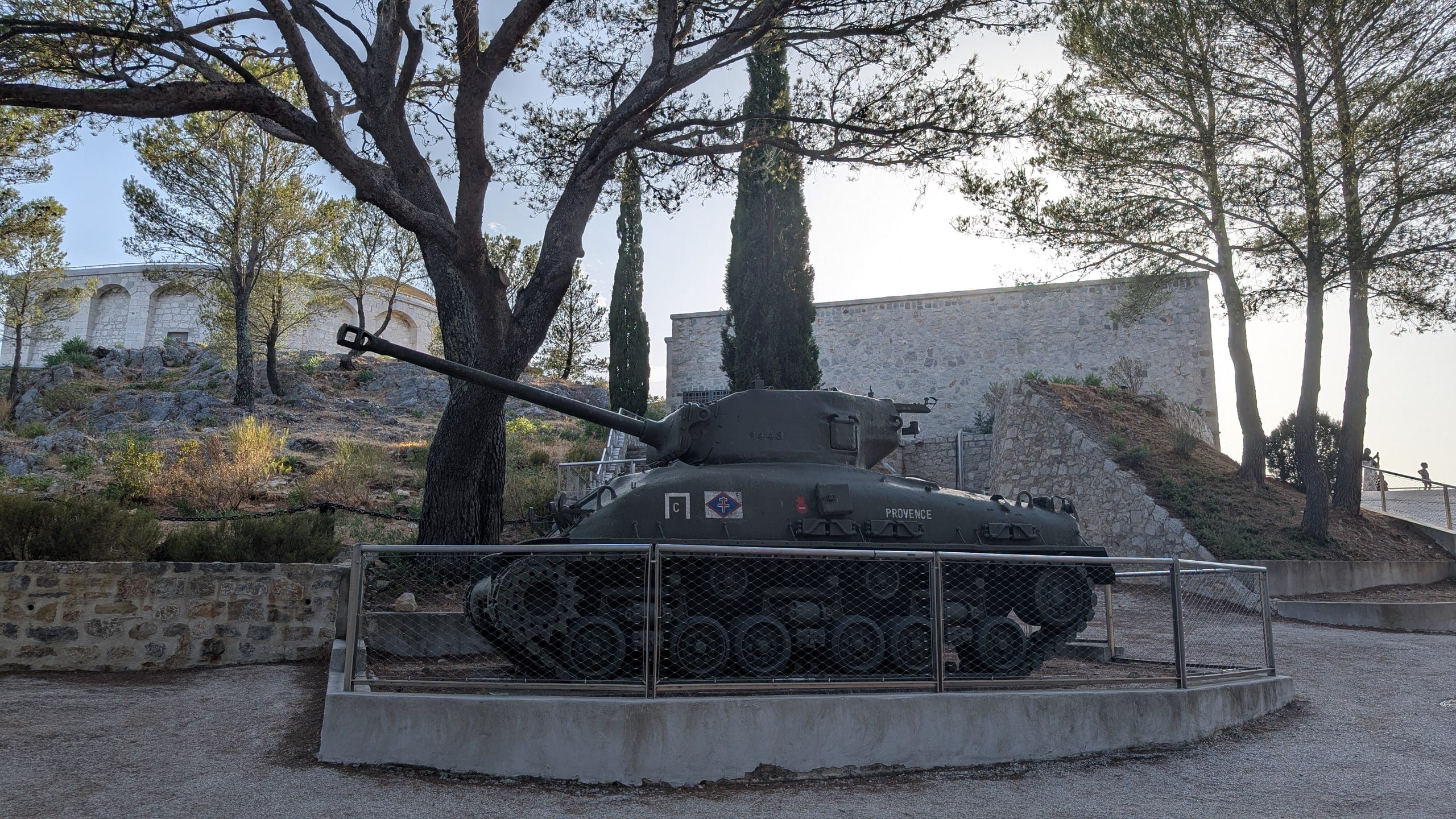 A Sherman tank named Provence displayed under pines and cypresses outside the Provence landings memorial at Tour Beaumont on Mont Faron